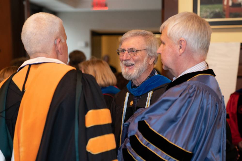 3 male faculty talking before convocation